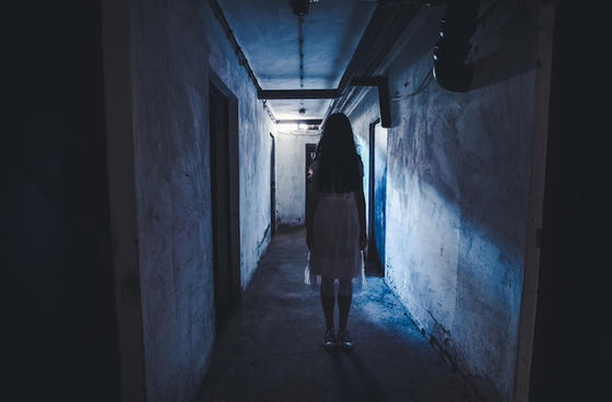 An image projects a suspenseful mood as the camera follows a young girl walking down a spooky hallway.